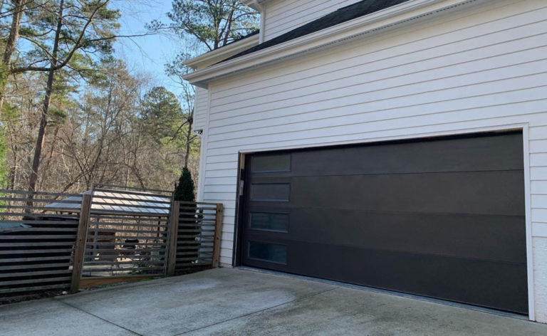 New black garage door on a white brick house sold by open door policy